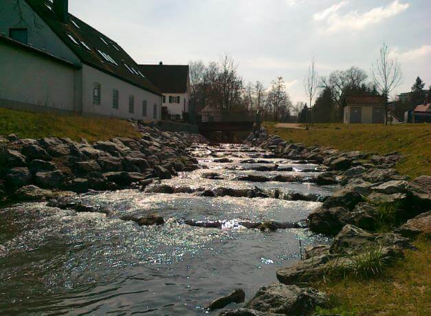 Renaturierte Uferzone mit einheimischen Pflanzen und verbessertem Wasserrückhalt in Langenneufnach.