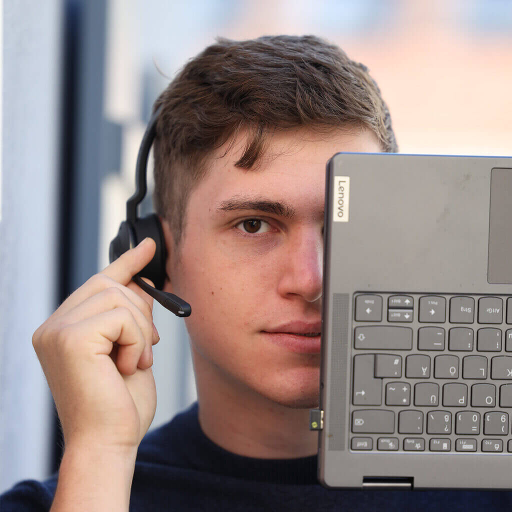Der Ausbildungsberuf Fachinformatiker bei GINGER HPC. Der Azubi Fachinformatiker hat sein Gesicht zur Hälfte mit einer Tastatur abgedeckt.