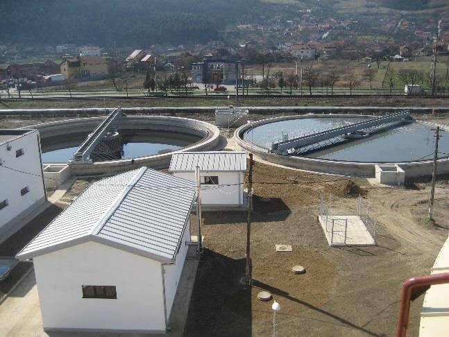 Bauarbeiter bei der Erweiterung der Kläranlage Deva, mit neuen Infrastrukturkomponenten im Hintergrund.